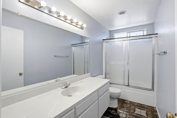 Bright and spacious bathroom featuring dual sinks, modern fixtures, and a large walk-in shower.