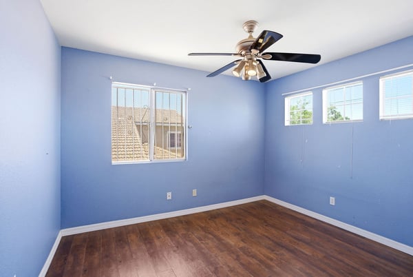 Bright and airy room featuring large windows, modern ceiling fan, and quality flooring for versatile use.