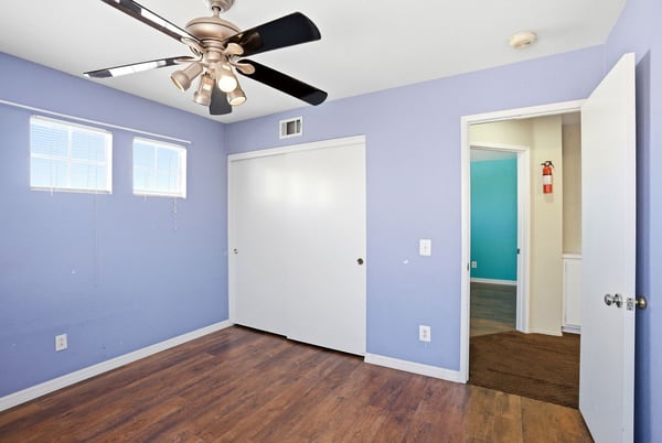 Bright and airy bedroom featuring a ceiling fan and convenient double-door closet for ample storage.