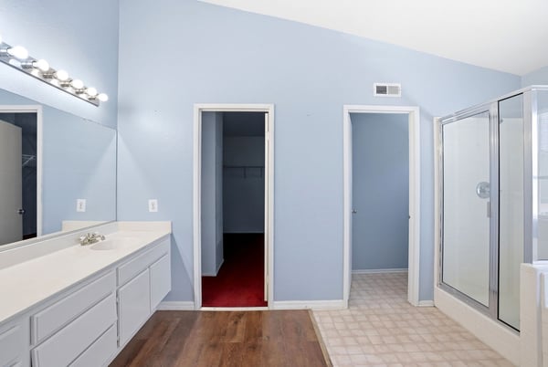Bright and spacious bathroom featuring modern fixtures, dual vanities, and a convenient walk-in closet.