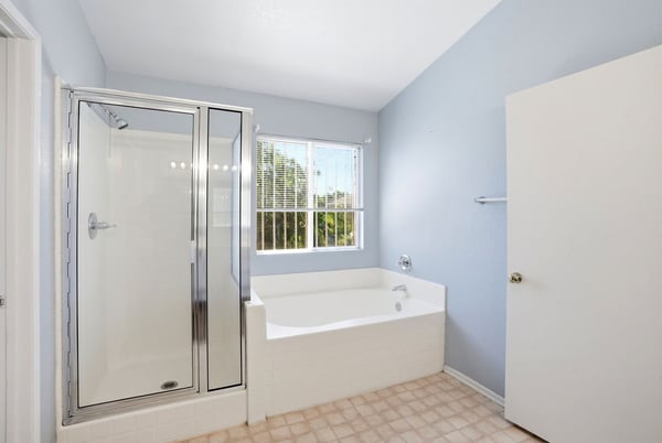 Bright and spacious bathroom featuring a separate shower, soaking tub, and natural light from large window.