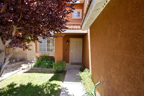 Inviting entryway leading to a cozy home, surrounded by lush greenery and vibrant landscaping.