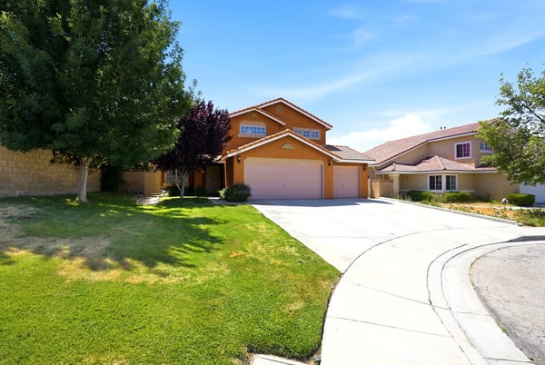 Spacious two-story home with a large yard, driveway, and vibrant landscaping in a quiet neighborhood.