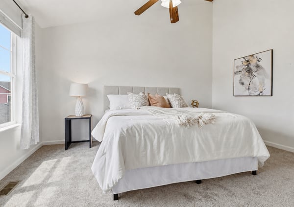 Bright and airy bedroom featuring large window, vaulted ceiling, neutral tones, and a comfortable layout for relaxation.