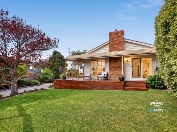 Nestled on a spacious lawn, this home features a welcoming porch and abundant outdoor greenery.