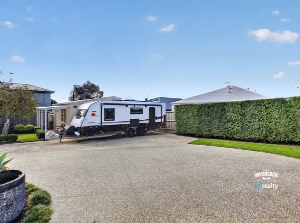 Spacious driveway perfectly accommodates an RV, surrounded by well-maintained landscaping for added privacy and convenience.