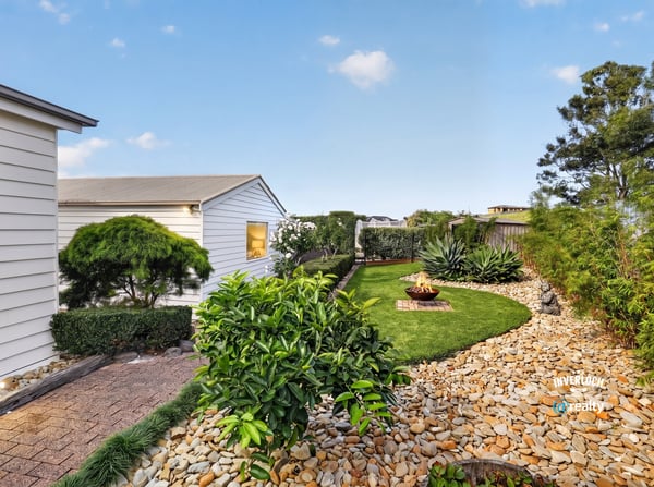 Discover a tranquil outdoor space featuring neat landscaping, unique planting beds, and a cozy fire pit area.