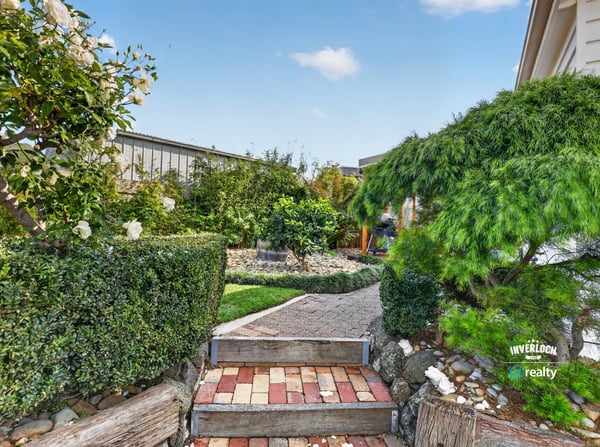 Discover a beautifully landscaped garden pathway surrounded by lush greenery and vibrant plant life.
