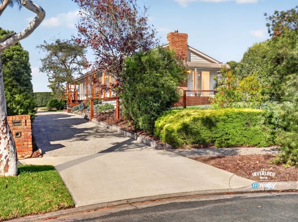 This spacious home features a picturesque landscape, inviting driveway, and ample outdoor space for entertaining.