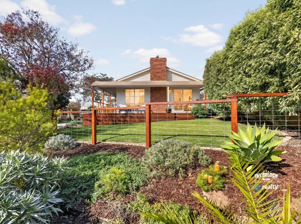 Discover a beautifully landscaped property featuring a spacious backyard with vibrant greenery and ample outdoor space.