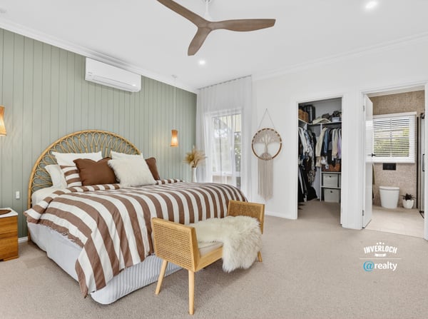 Spacious bedroom featuring unique decor, natural light, and convenient access to an organized closet and bathroom.