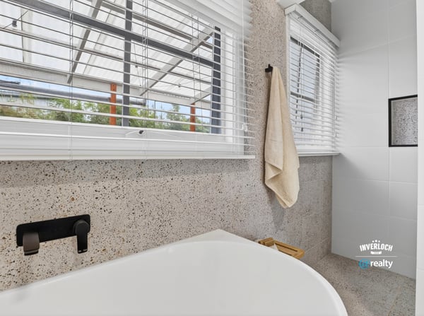 Bright and modern bathroom featuring a spacious tub and large windows for ample natural light.
