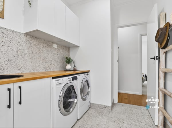Bright laundry area featuring modern appliances, streamlined cabinetry, and a clean, functional design.