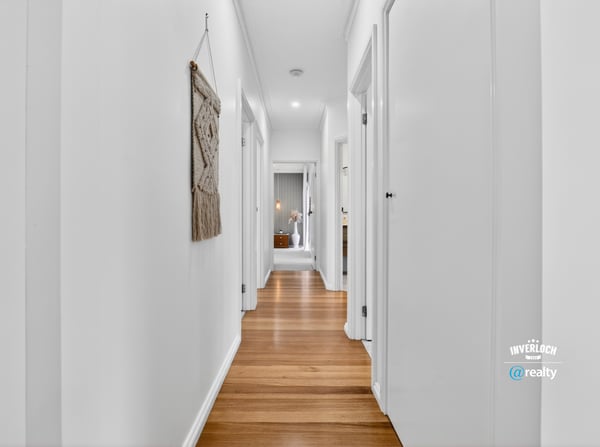 Bright and inviting hallway featuring warm wooden floors and a modern, open layout.