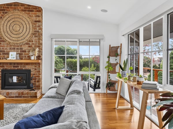 Bright, inviting living space featuring a cozy fireplace and panoramic views of the surrounding gardens.