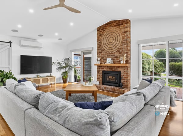 Spacious living area features a cozy fireplace, ample natural light, and direct access to outdoor views.