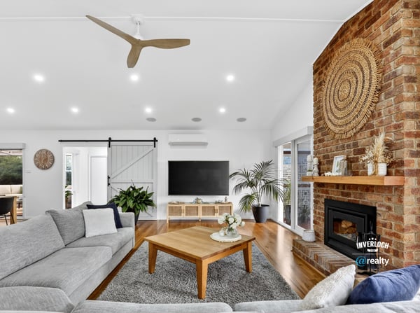 Bright and inviting living space featuring a striking brick fireplace and modern ceiling fan, perfect for gatherings.