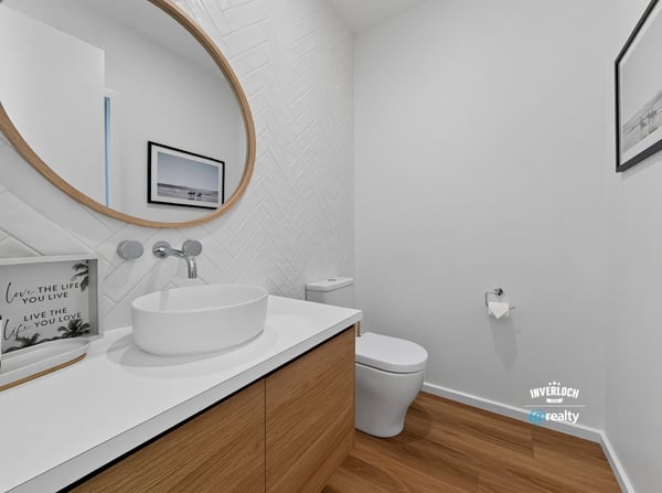 Bright and modern bathroom featuring a unique round mirror and sleek wood cabinetry for functional appeal.
