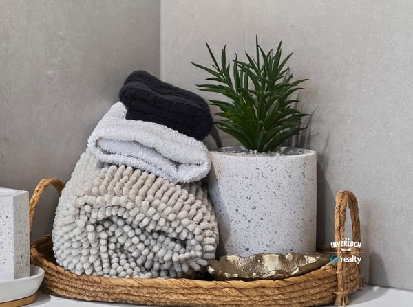 This inviting bathroom features neatly arranged towels and a contemporary plant in a chic basket.