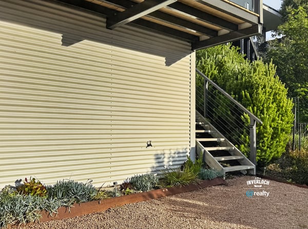 Modern exterior featuring a sleek design, landscaped garden, and convenient access via inviting stairs.