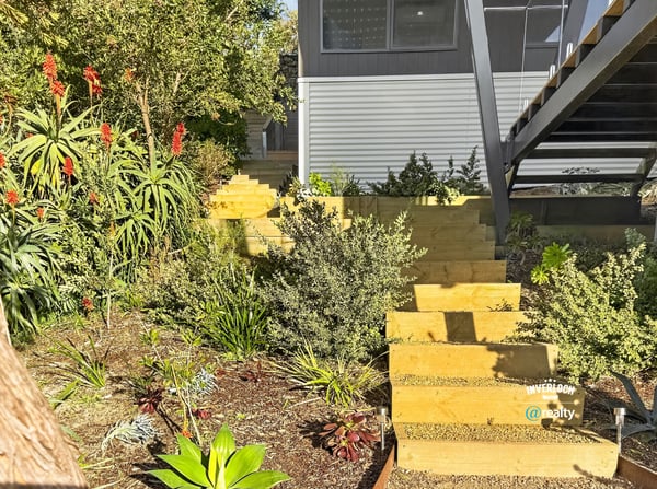 This unique home features a beautifully landscaped garden with inviting wooden steps leading to an open entry.