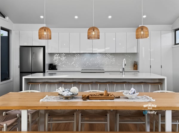 Modern open-plan kitchen featuring sleek cabinetry, a spacious dining area, and unique pendant lighting.