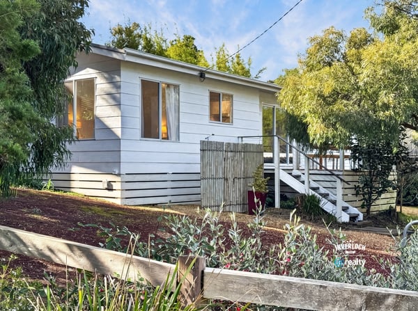 This inviting home features ample windows, a spacious outdoor area, and a welcoming front porch.
