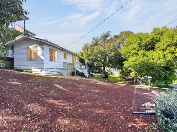 Bright, inviting home on a hillside lot, featuring expansive outdoor space and potential for personalization.