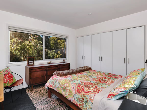Bright bedroom featuring ample storage, a comfortable bed, and large windows showcasing natural surroundings.