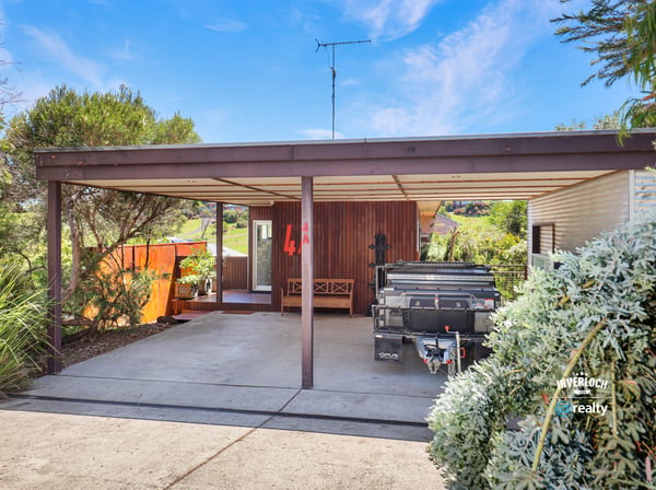 This property features a spacious carport, landscaped surroundings, and a unique architectural design, ideal for customization.