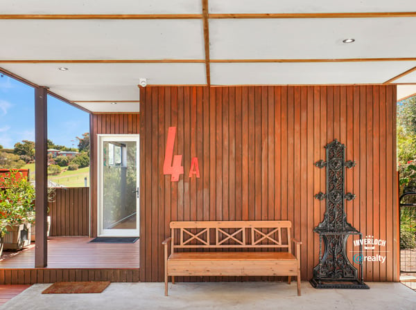 Modern entrance featuring a unique wooden design, inviting natural light and showcasing outdoor views.