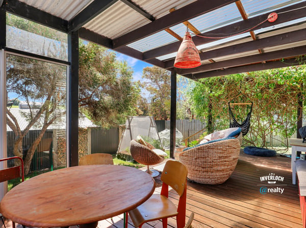 Relax in this inviting outdoor space with a cozy seating area, surrounded by lush greenery.