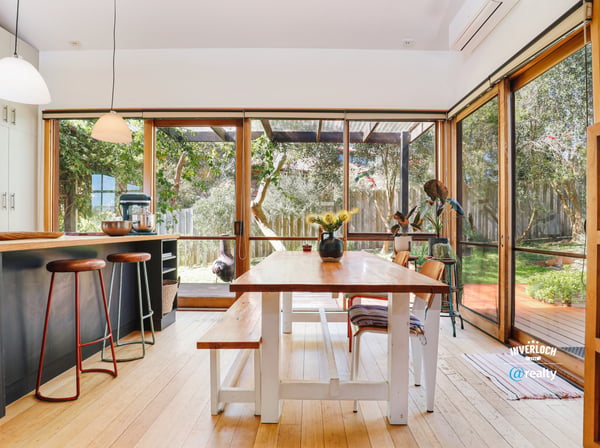 Bright and inviting kitchen and dining area seamlessly connect to a lush outdoor space, perfect for gatherings.