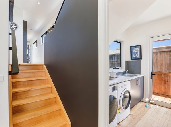 Modern entryway features a bright, airy stairway alongside a convenient laundry area and outdoor access.