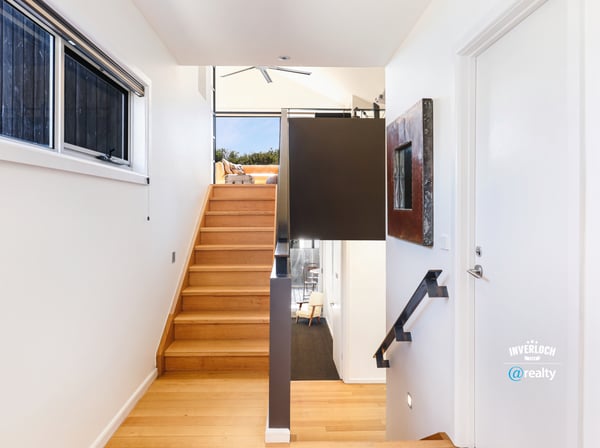 Bright entryway with modern design, featuring warm wood accents and an inviting staircase leading to open spaces.