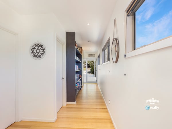 Bright and inviting hallway with seamless flow, showcasing built-in shelves and modern design elements.