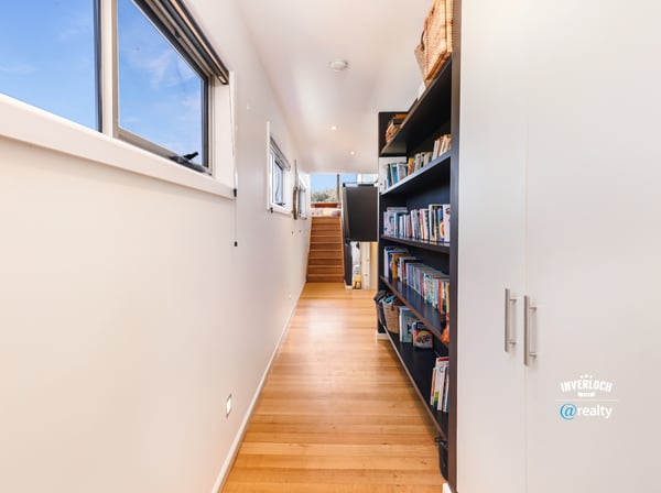 Bright and inviting hallway features built-in shelving, leading to a spacious upper-level living area.
