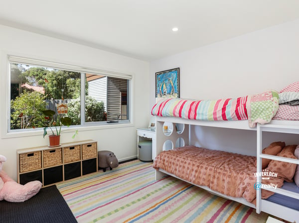 Bright and inviting bedroom featuring bunk beds, ample storage, and a large window overlooking the garden.