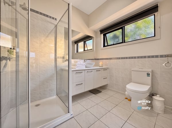 Bright, modern bathroom featuring a spacious shower, sleek cabinetry, and ample natural light for daily comfort.