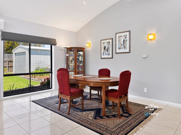 Bright dining area featuring large windows, a wooden table, and vibrant red chairs, perfect for gatherings.