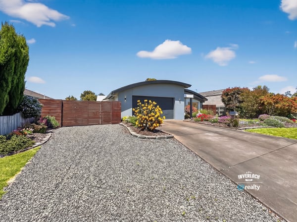 Beautifully landscaped exterior greets you, featuring a spacious driveway and inviting entrance to a modern home.
