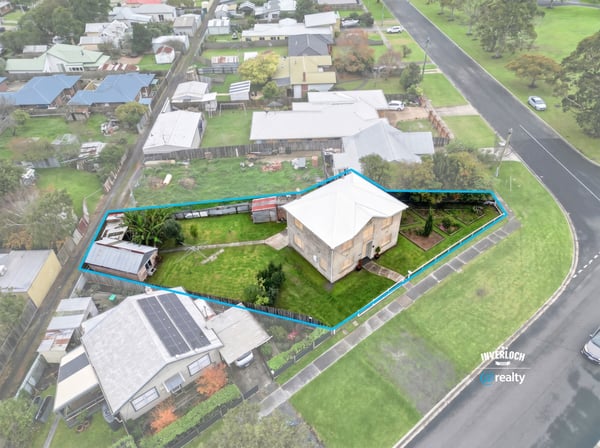 Spacious corner lot with potential for development, featuring a two-story home and ample outdoor space.