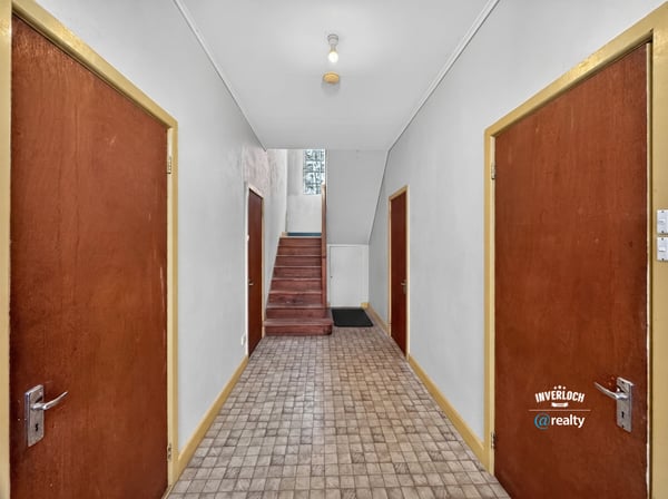 Spacious hallway with wooden doors, leading to a staircase and inviting natural light throughout the space.