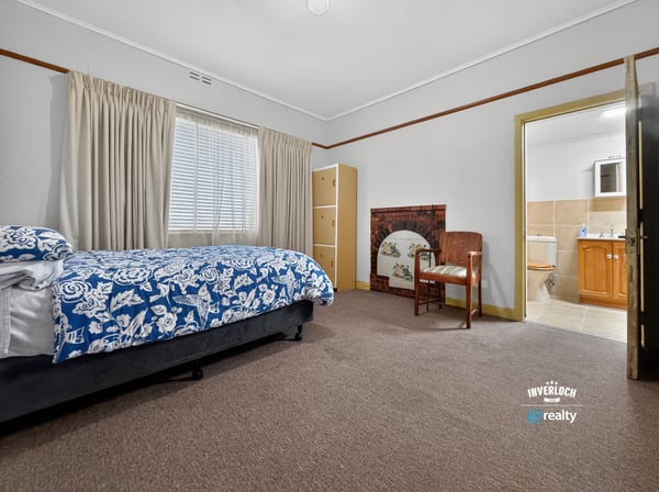 Spacious bedroom featuring natural light, a cozy seating area, and convenient access to an ensuite bathroom.