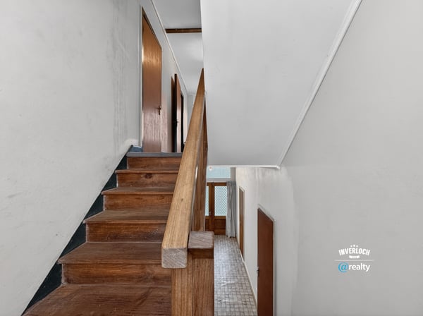 Bright and spacious staircase leading to additional living areas, featuring hardwood accents and natural light.
