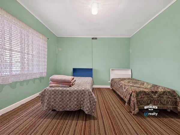 Bright and spacious bedroom with ample natural light, featuring two beds and distinctive patterned accents.