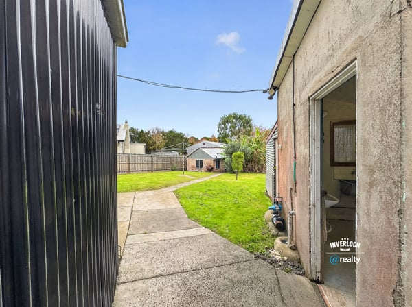Spacious backyard with landscape potential, featuring accessible pathways and neighboring properties for a vibrant community feel.