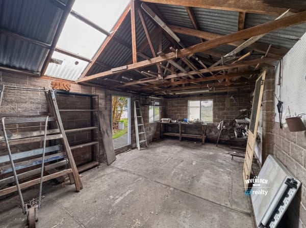 Spacious workshop with ample storage potential, featuring high ceilings and natural light for creative projects.