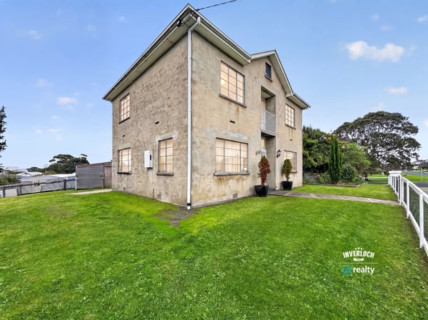Spacious multi-level property on a generous lot, featuring large windows and expansive green yard.