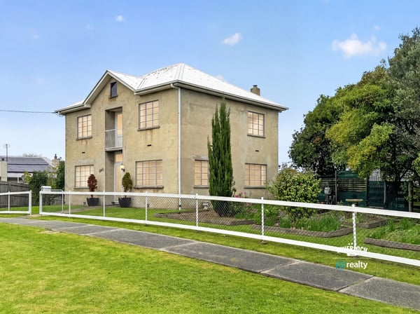 This spacious two-story home features large windows, a manicured lawn, and ample outdoor space for gatherings.